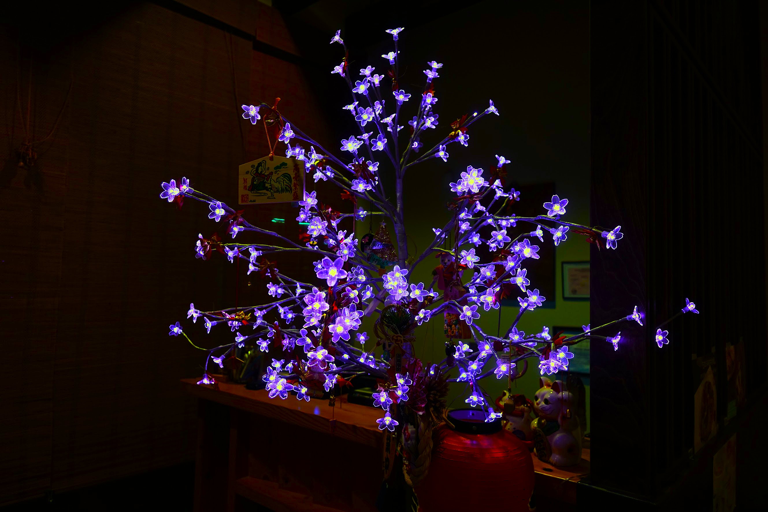 Illuminated artificial blossom tree glowing violet in a dark room