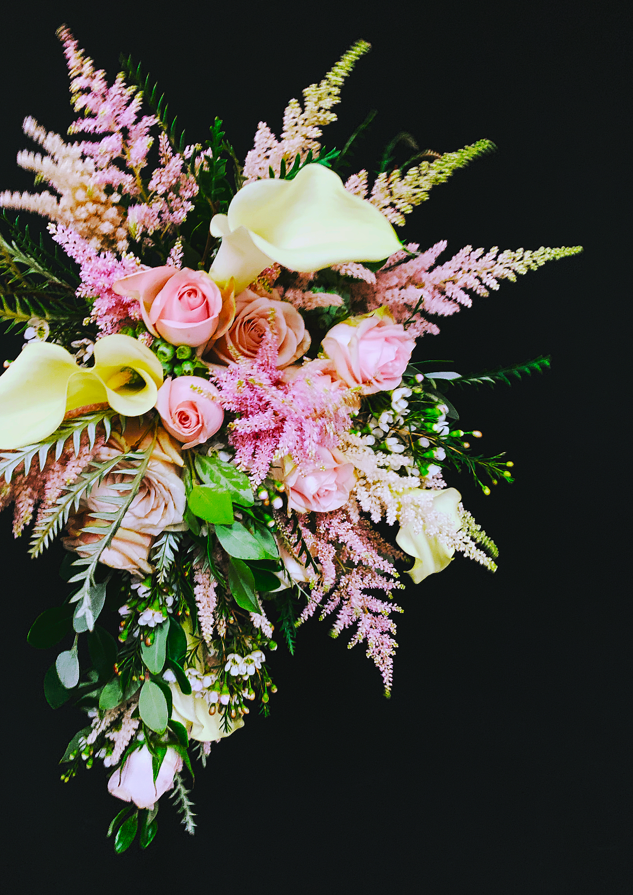Cascading bouquet of astilbe and calla on a dark ground